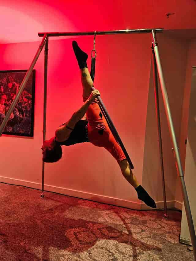 Aerial performer at Spinning Pole in GFFdamian Dance Studio, vibrant red lighting. Event entertainment.