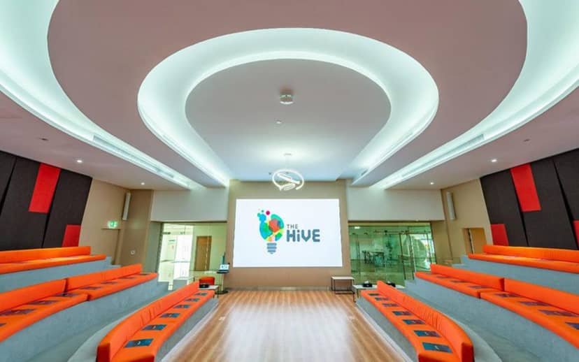 Modern conference hall in ADNEC, featuring orange seating and projection area for workshops.