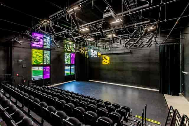 Modern black box theater with colorful windows for versatile events and performances.