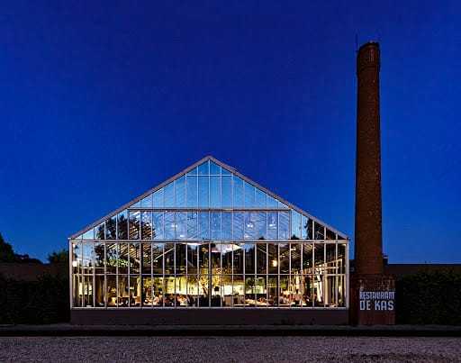 "Modern glass restaurant De Kas, ideal for events with vibrant ambiance and natural elements."