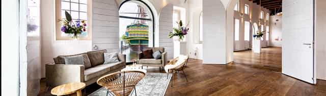 Modern event space with large window and colorful ship view at Het Scheepvaartmuseum.