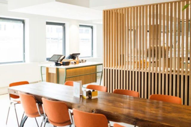 Modern meeting room with wooden table and vibrant orange chairs for workshops and presentations.