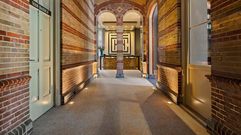 Elegant Van Baerle Salon corridor with warm brick, perfect for meetings and events.