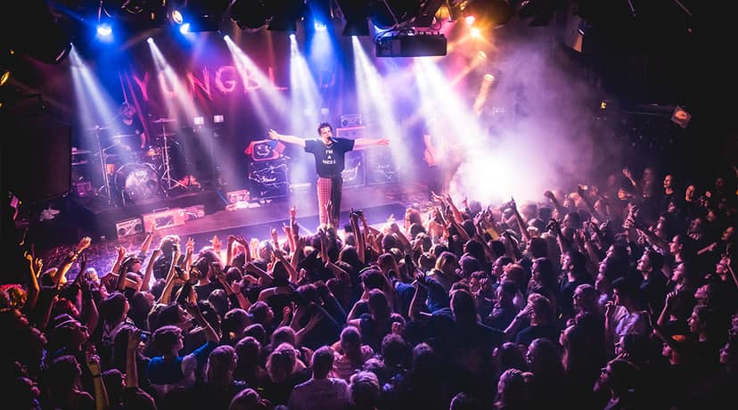 "OZ live performance at Melkweg with vibrant lights and an engaged crowd."