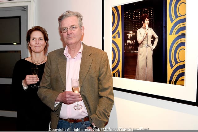 Networking event in art gallery with attendees enjoying drinks and conversation.