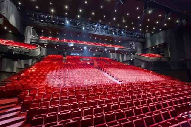 Modern auditorium with tiered red seating, perfect for conferences and performances.