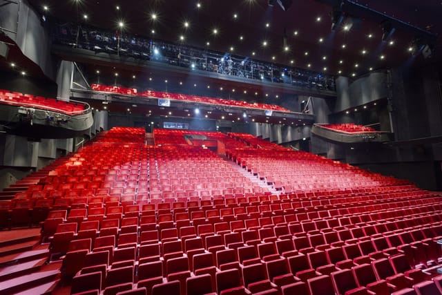 Modern auditorium with tiered red seating, perfect for conferences and performances.