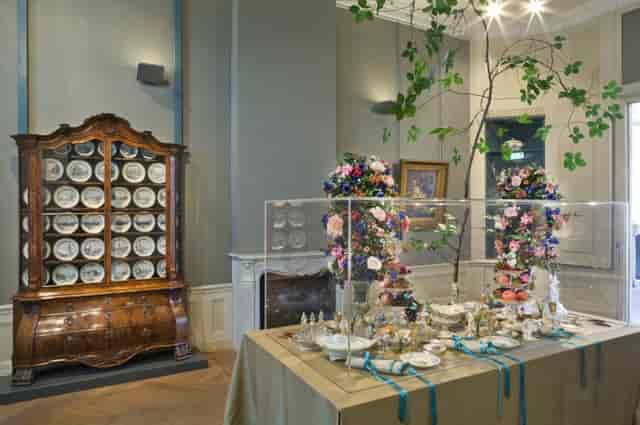 Elegant exhibition display in Cromhout House with floral arrangements and fine china.