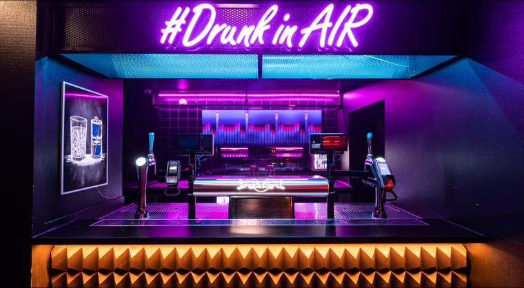 Modern bar setup in Amsterdam with neon "#DrunkinAIR" signage for vibrant events.