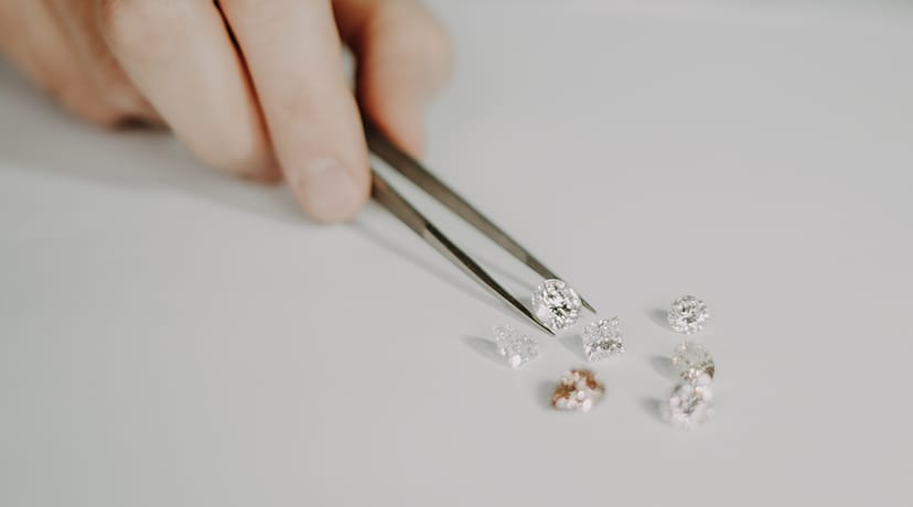 Hand with tweezers selecting diamonds at GASSAN Historical Tour, showcasing event precision.