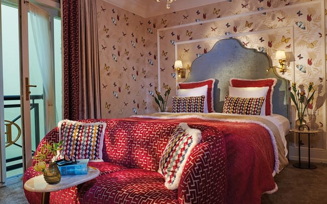 Stylish Herrenzimmer hotel room with vibrant wallpaper for VIP event accommodation.