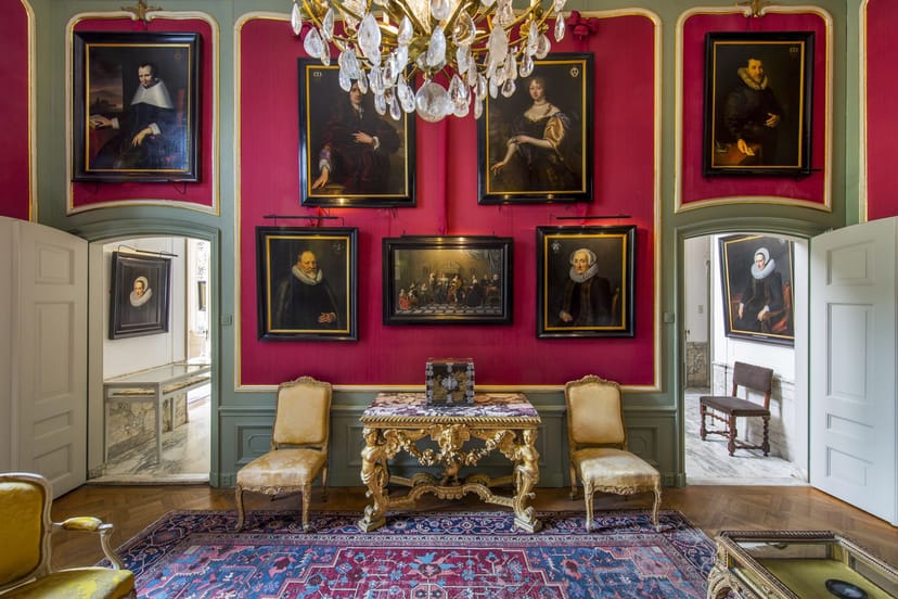 Elegant meeting room with red walls and chandelier at Museum Van Loon for upscale events.