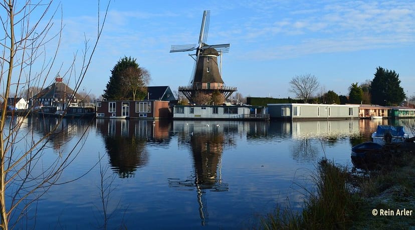 Traditional windmill by tranquil water at Molen van Sloten, ideal for outdoor events.
