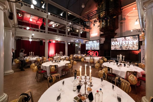 Elegant dinner setup in Rode Hoed Main Hall with round tables and candelabras.