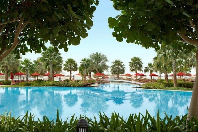 Poolside gardens at Khalidiya Palace with lush greenery, ideal for networking events.