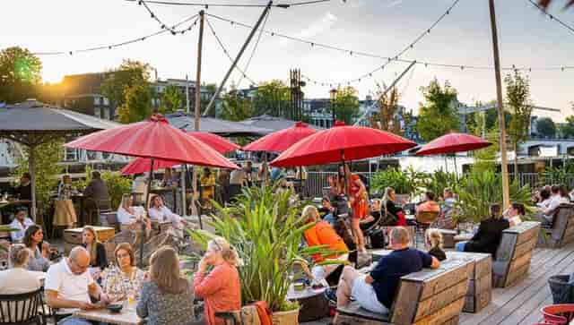 Vibrant outdoor networking event at Royal Amsterdam terrace with red umbrellas.