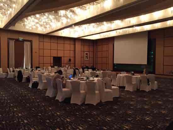 Liwa Grand Ballroom, elegant conference event space with round tables and chandeliers.