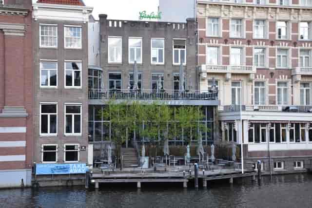 Charming waterfront café patio with glass facade, ideal for meetings and events.