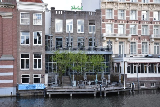 Charming waterfront café patio with glass facade, ideal for meetings and events.
