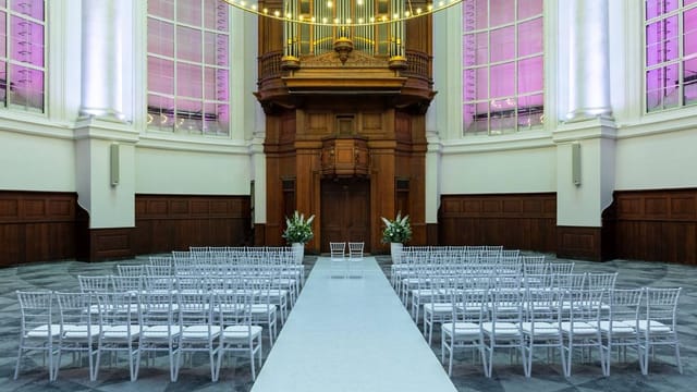 Elegant Renaissance Amsterdam Hotel meeting room with white chairs set for a wedding ceremony.