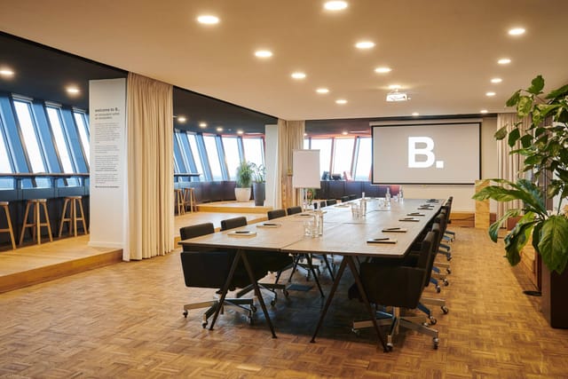 Modern boardroom in B. Amsterdam with large windows, perfect for collaborative meetings.