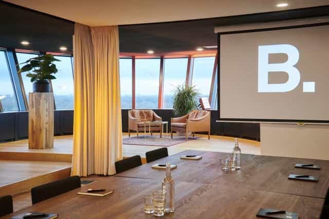 Modern boardroom in B. Amsterdam with large windows, ideal for meetings and presentations.