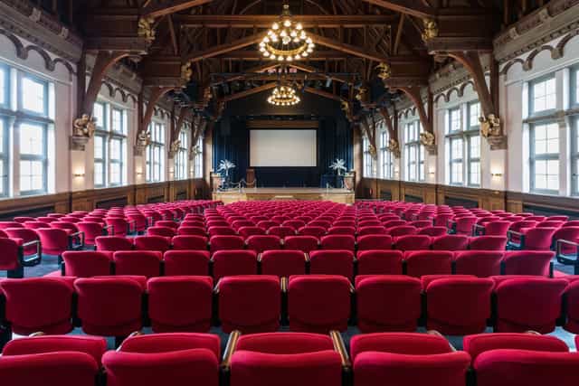 Koningin Máxima Zaal auditorium with red chairs, perfect for corporate conferences and seminars.