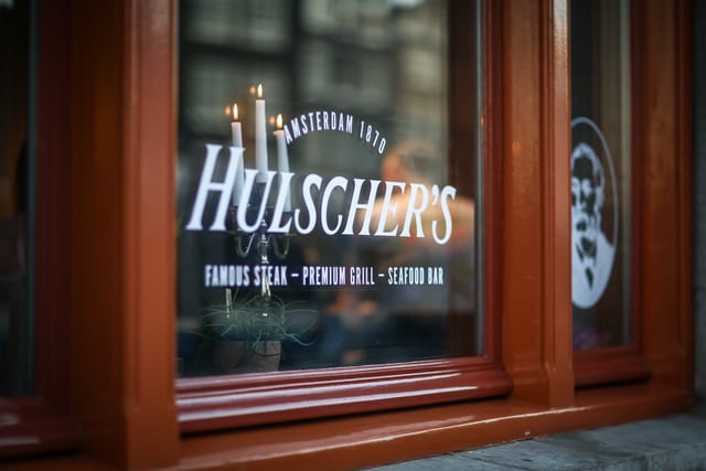 Hulscher's restaurant window, featuring elegant steak and seafood dining for private events.