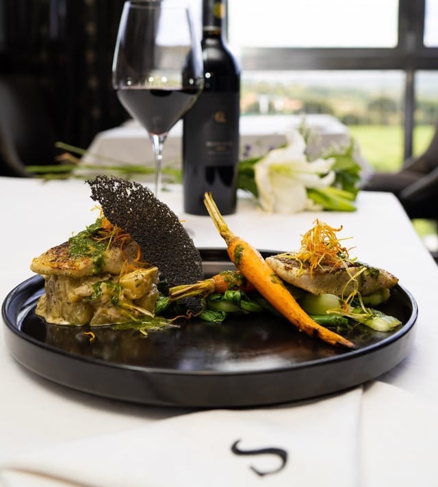 Gourmet dish with vibrant vegetables and fish for upscale dining events.