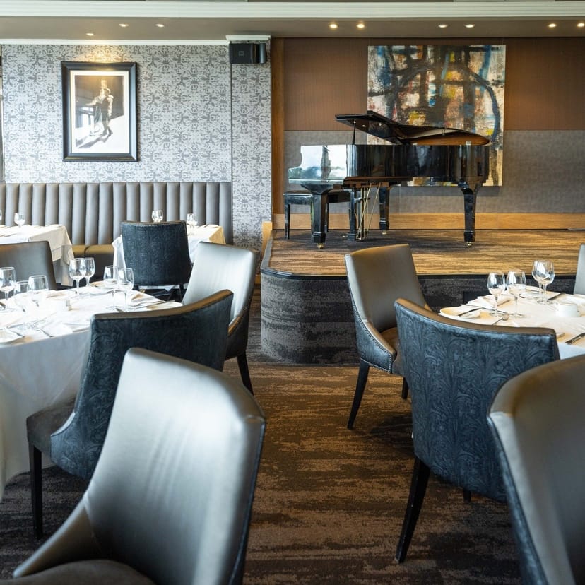 Elegant restaurant setting with grand piano, perfect for upscale events and corporate dinners.