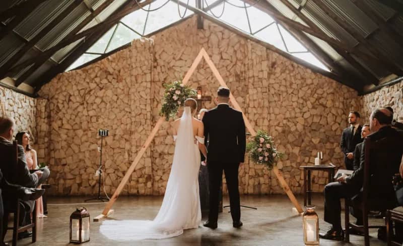 Romantic wedding ceremony at rustic Trés Jolie venue with elegant wooden altar.