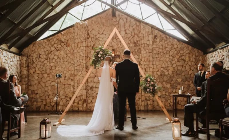 Romantic wedding ceremony at rustic Trés Jolie venue with elegant wooden altar.