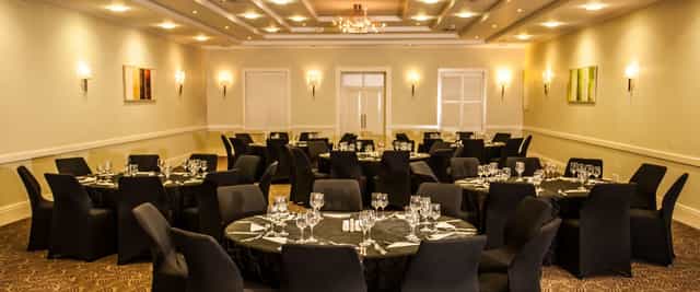 Auctioneers in Gold Reef City banquet room set for upscale corporate event with elegant tables.