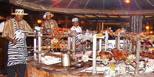 Outdoor dining setup with chefs grilling meats for weddings and festivals.