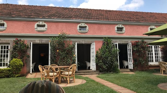 Outdoor meeting space with rustic pink building, perfect for networking events at Muthaiga Country Club.
