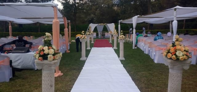 Elegant outdoor wedding venue with floral arrangements and decorated arch.