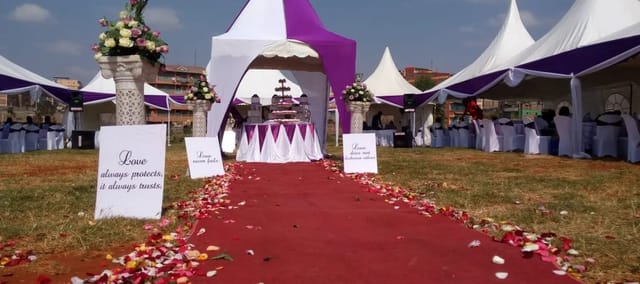 Outdoor wedding event with white and purple tents and rose petal path.
