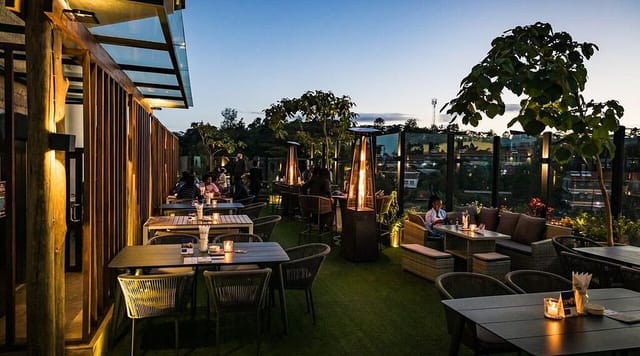 Rooftop bar in The Forest Adventure Centre, set for evening networking event with fire pits.