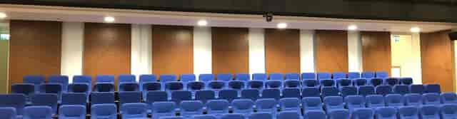 Modern conference hall with blue seating, ideal for lectures and events.