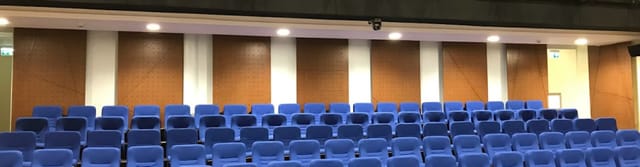 Modern conference hall with blue seating, ideal for lectures and events.
