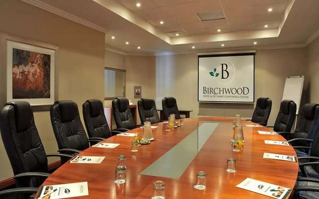 Boardroom at Birchwood Hotel with polished table, ideal for corporate meetings and events.
