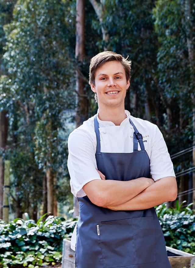 Smiling chef in professional attire promotes culinary event catering services.