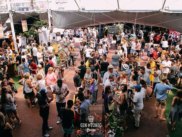 Outdoor conference event at The Old Biscuit Mill with a large crowd under a spacious tent.