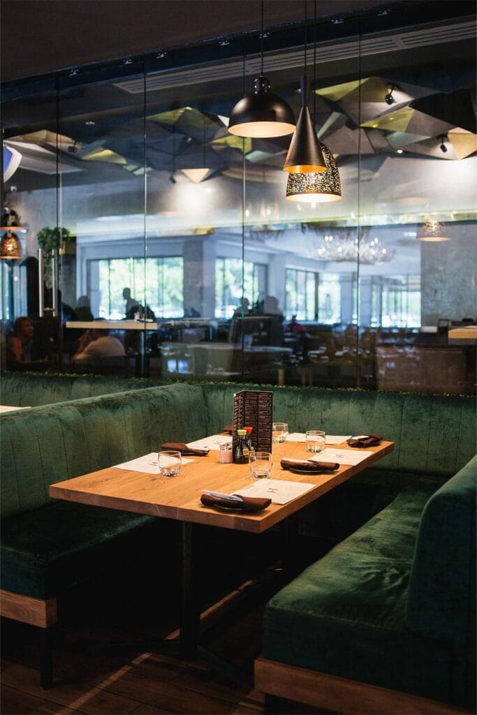Elegant dining setup with plush green seating for intimate events in Fireroom restaurant.