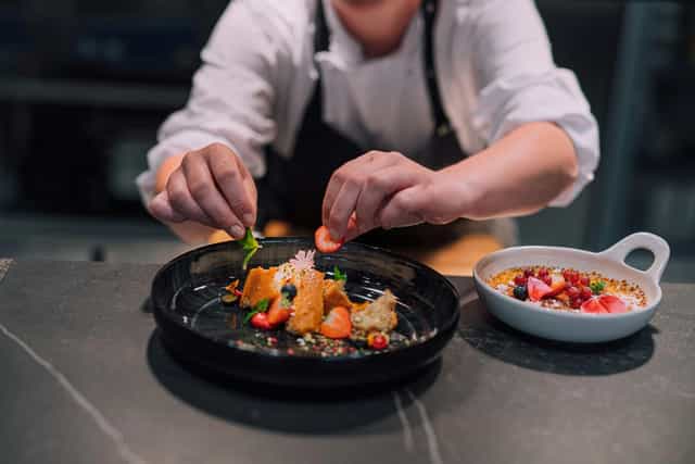 Chef plating vibrant dish on Bistro ELO rooftop terrace for elegant event dining.