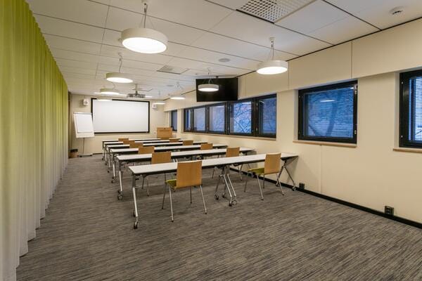 Kuntatalo lobby meeting space with tables and chairs, ideal for workshops and training.