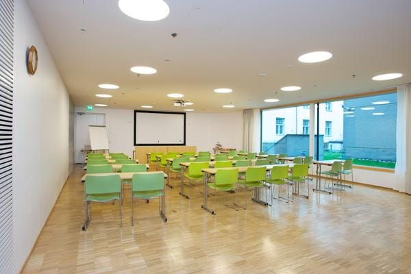 Bright meeting room with green chairs, ideal for workshops and training sessions.