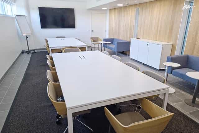 Modern meeting room with white table and ergonomic chairs for workshops in Urheiluhallit.