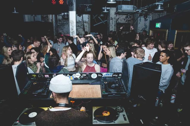 Lively nightclub scene in SOUP Manchester with dancing crowd and DJ setup, nightlife event.