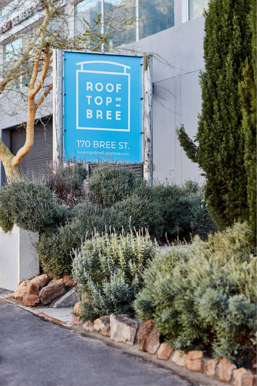 Outdoor rooftop deck venue entrance with greenery, ideal for events and gatherings.